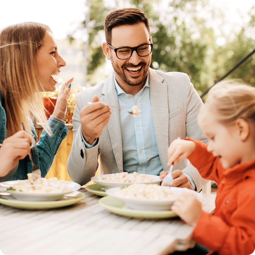 Happy family laughing and eating together outside on a sunny patio